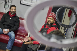 Two men sitting on red bench seats.