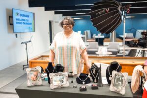 A woman standing at an exhibitor table, smiling.